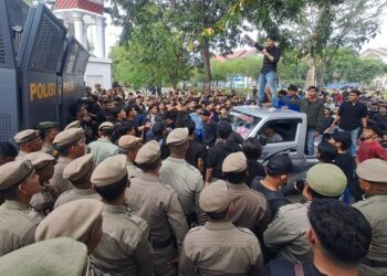 Massa dari Aliansi Rakyat Aceh berunjuk rasa di depan gerbang Kantor Gubernur Aceh menuntut penandatanganan petisi JKA, Senin (18/5/2026).