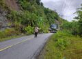 Petugas kepolisian mengatur arus lalu lintas kendaraan dengan sistem buka-tutup di samping material longsor yang menutupi jalan nasional di Tangse, Pidie.